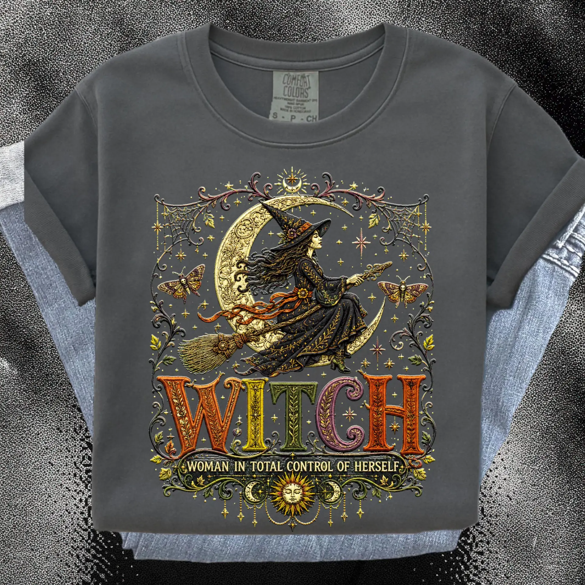 Charcoal garment-dyed t-shirt with an ornate print of a witch riding a broom across a golden crescent moon above the words WITCH, Woman in Total Control of Herself