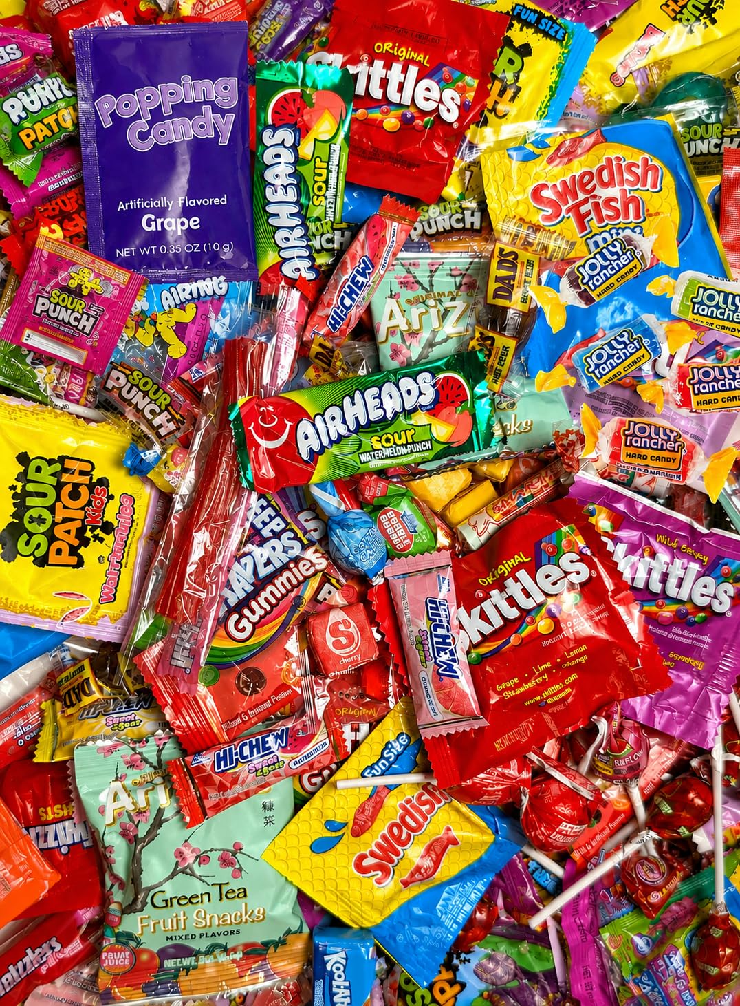 A large colorful assortment of individually wrapped candy including Skittles, Airheads, Sour Patch Kids, Swedish Fish, Jolly Ranchers and lollipops