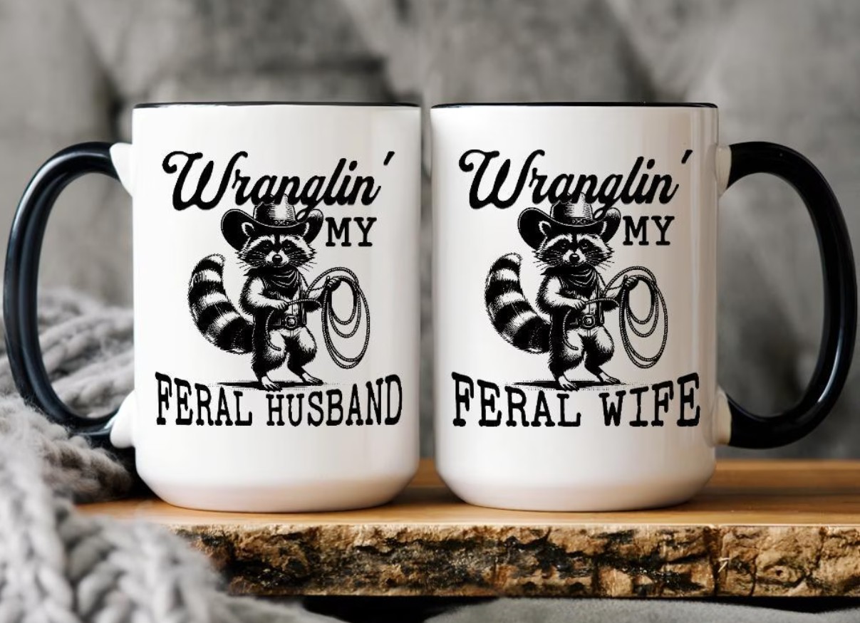 Funny 'Wranglin' My Feral Husband' and 'Wranglin' My Feral Wife' matching black-handled ceramic couple coffee mug set with cowboy raccoon illustrations