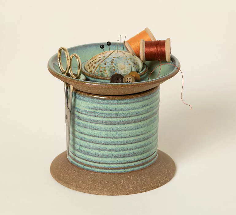 Handmade blue-green ceramic sewing caddy with pincushion top, scissors, thread, pins, and buttons