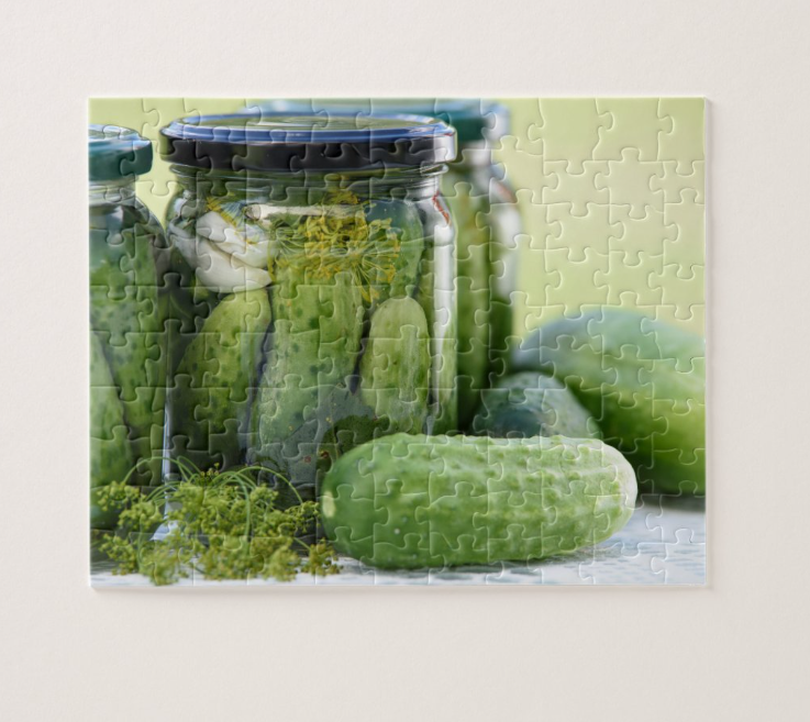 Assembled jigsaw puzzle showing a close-up photograph of jars of dill pickles with fresh dill and whole cucumbers