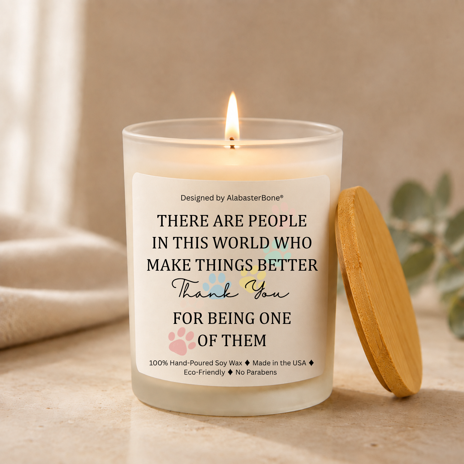 Frosted glass soy candle with a bamboo lid, labeled There are people in this world who make things better, thank you for being one of them, with pastel paw prints