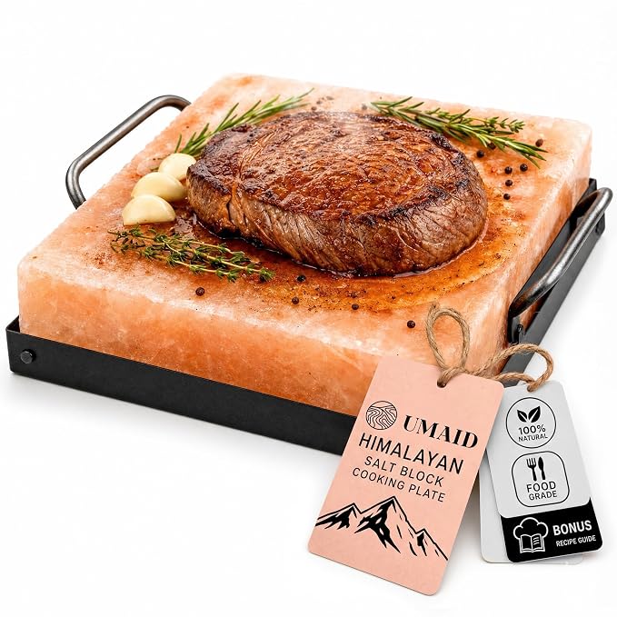 Pink Himalayan salt block in a metal serving frame with a seared steak, garlic and fresh herbs on top