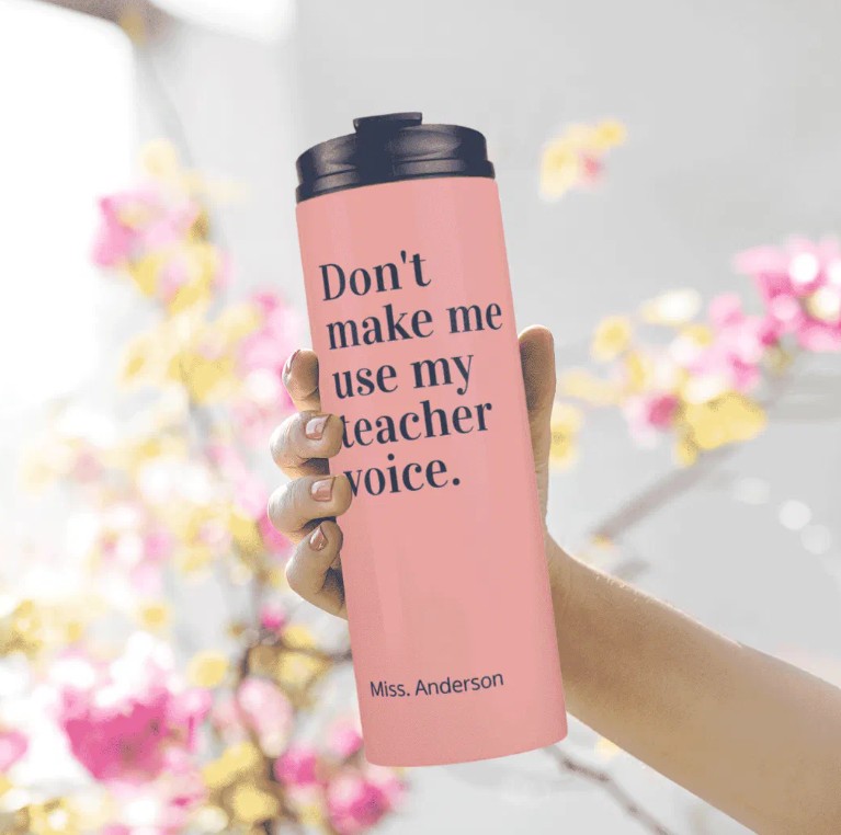 Pink insulated teacher travel mug tumbler with bold black 'Don't make me use my teacher voice.' quote and 'Miss. Anderson' name printed at the bottom